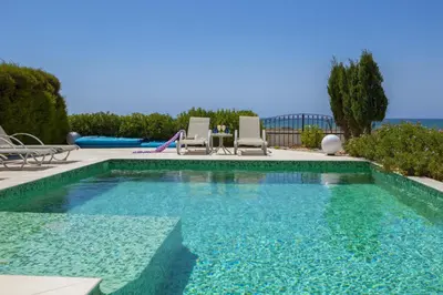 a swimming pool with two chairs and a slide at Ayia Thekla Seafront Villa Lavender in Ayia Napa