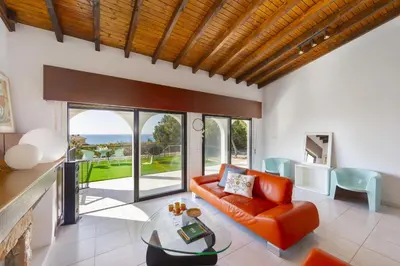 a living room with an orange couch and a glass table at Ayia Napa Ammos Sea View Villa in Ayia Napa