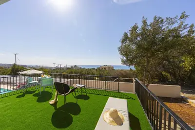 a balcony with a table and chairs on the grass at Ayia Napa Ammos Sea View Villa in Ayia Napa