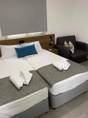 a bedroom with two beds and a chair at ElleNapa Apts & Studios in Ayia Napa