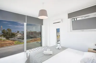 a bedroom with white walls and a large window at Villa Naya in Protaras