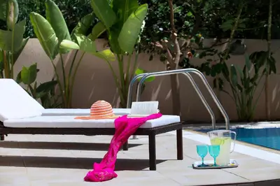 a pool with a chaise lounge with a hat and two glasses at Protaras Villa Michelle 9 in Protaras