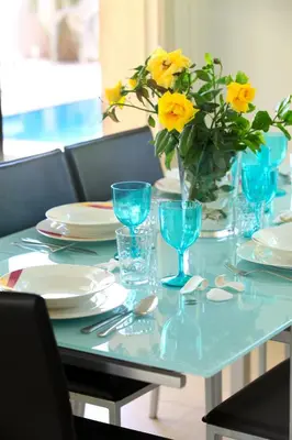 a blue table with a vase of yellow flowers on it at Protaras Villa Michelle 9 in Protaras