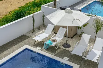 an umbrella and chairs next to a swimming pool at Protaras Villa Alasia in Protaras