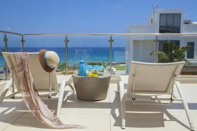 a patio with chairs and a hat on a balcony at Central Protaras Seaview Villa Zinnia in Protaras