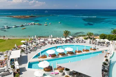 an aerial view of a resort with a pool and the ocean at King Jason Protaras - Designed for Adults by Louis Hotels in Protaras