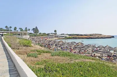 a beach with umbrellas and people sitting on the beach at Villa Katherine - Nissi Beach Area in Ayia Napa