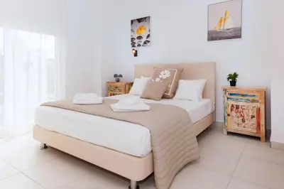 a bedroom with a large bed with white sheets at Villa Katherine - Nissi Beach Area in Ayia Napa