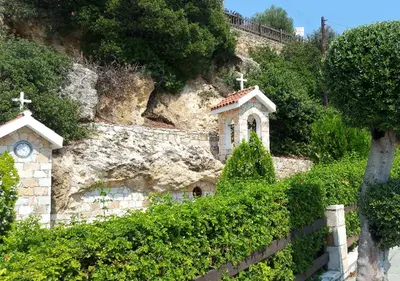 a small church with a clock on the side of a hill at Apokryfo, one bedroom apartment close to the beach in Pissouri