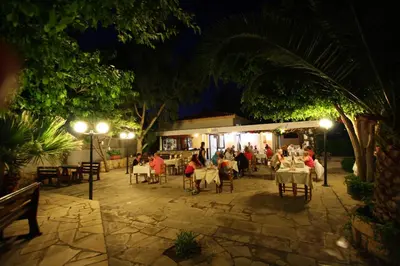 a group of people sitting at a restaurant at night at Apokryfo, one bedroom apartment close to the beach in Pissouri