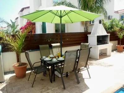 a table and chairs under a green umbrella on a patio at Luxury Villa - Private Pool and Wifi Perfect location for a holiday in Protaras