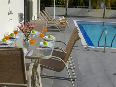 a table and chairs next to a swimming pool at Protaras Villa Theodora 1 in Protaras