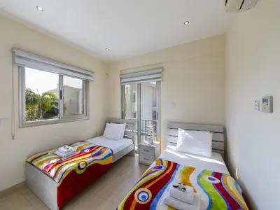 two beds in a room with two windows at Protaras Villa Theodora 1 in Protaras