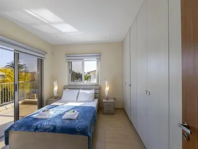 a bedroom with a bed and a balcony at Protaras Villa Theodora 1 in Protaras