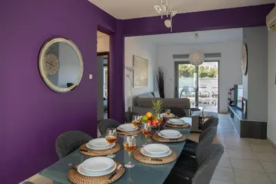 a dining room with a table and chairs and a purple wall at Villa Ruby Yiasemina in Ayia Napa