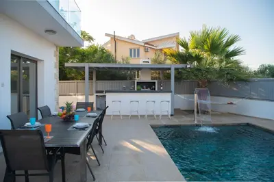 a patio with a table and a swimming pool at Villa Ruby Yiasemina in Ayia Napa