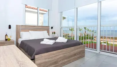 a bedroom with a bed and a balcony with the ocean at Villa Ivory - Seafront in Ayia Napa