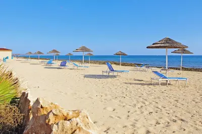 a group of chairs and umbrellas on a beach at Villa Ivory - Seafront in Ayia Napa