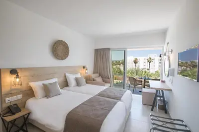 a hotel room with a large bed and a table at Bohemian Gardens Hotel in Protaras