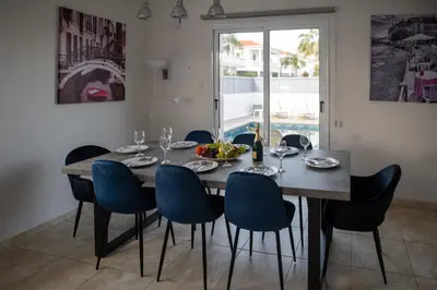 a dining room with a wooden table and blue chairs at Villa Ruby Nissi Beach in Ayia Napa