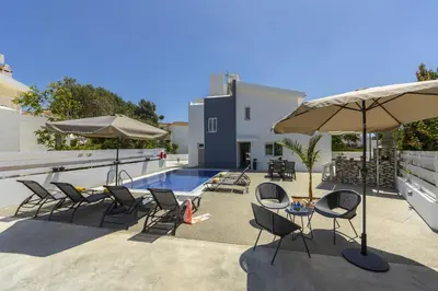 a group of chairs and umbrellas next to a pool at Villa Alleli in Protaras