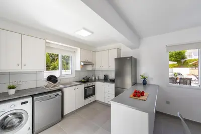 a white kitchen with a sink and a dishwasher at Villa Alleli in Protaras