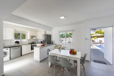 a white kitchen with a white table and chairs at Villa Alleli in Protaras