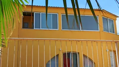 a yellow house with windows on a balcony at Olimpus Garden Homes in Ayia Napa