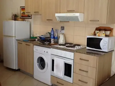 a kitchen with a white stove top oven next to a refrigerator at Olimpus Garden Homes in Ayia Napa