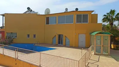 a yellow house with a swimming pool in front of it at Olimpus Garden Homes in Ayia Napa