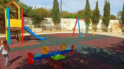 a little girl is playing on a playground at Olimpus Garden Homes in Ayia Napa
