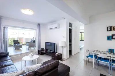 a living room with a couch and a tv and a table at Lovely 2 BR Vacation Apt Kohili Beach - 3 Min Walk in Paralimni