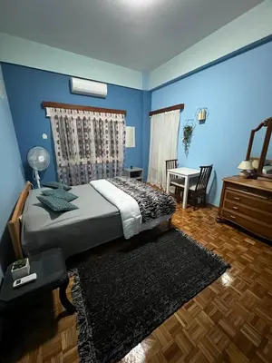 a bedroom with blue walls and a bed and a table at Past or Tail rooms in Larnaka