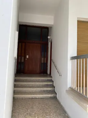 a stairway leading to a wooden door with stairs at Past or Tail rooms in Larnaka