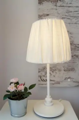 a white lamp sitting on a table next to a potted plant at Furnished Seafront Studio in Larnaka