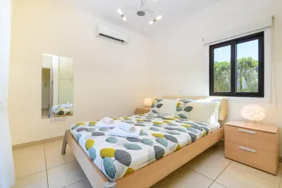 a bedroom with a bed and a window and a mirror at Protaras Centro Villa in Protaras