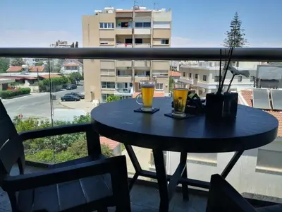 a table on a balcony with two glasses of beer at Loizou Holdings Flat 301 in Larnaka