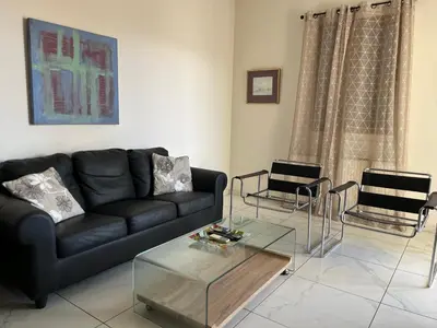 a living room with a black couch and a glass table at Klimentos Flat 58 in Nicosia