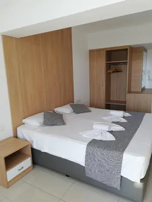 a bedroom with a large bed with white sheets at JOY Hotel Apts in Ayia Napa