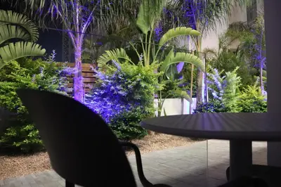 a table and chairs in a garden with purple flowers at JOY Hotel Apts in Ayia Napa