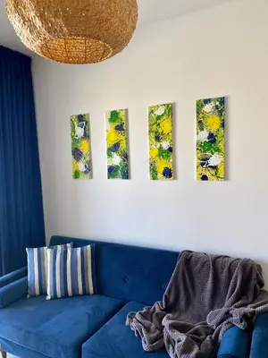 a living room with a blue couch and four paintings on the wall at Fat Cow Apartment 102 in Livadhia