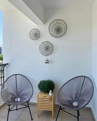 two chairs sitting in front of a white wall with mirrors at Fat Cow Apartment 102 in Livadhia