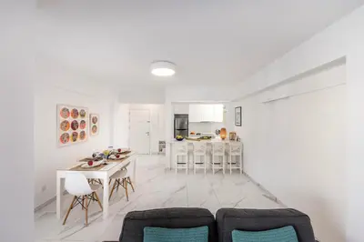 a living room and kitchen with a table and chairs at Mackenzie Leo Seafront Suite in Larnaka