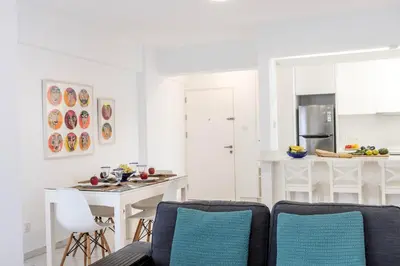 a white kitchen with a white table and chairs at Mackenzie Leo Seafront Suite in Larnaka