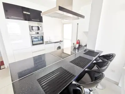 a kitchen with a black counter top and black chairs at Mackenzie Seaview Paradise in Larnaka