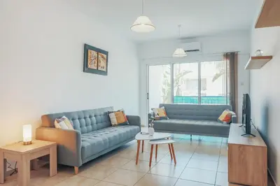 a living room with two blue couches and a tv at Elegant 1 Bedroom Apartment - Great Kings Resort Protaras, Kapparis in Paralimni