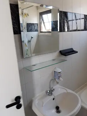 a white bathroom with a sink and a mirror at La Veranda Sea View apartments in Larnaka
