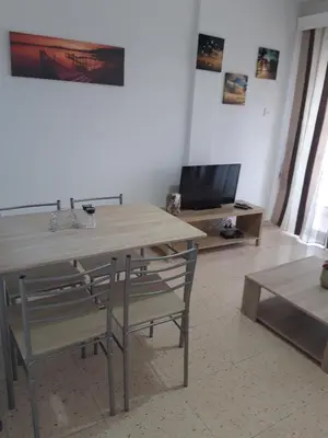 a table and chairs in a living room with a television at La Veranda Sea View apartments in Larnaka