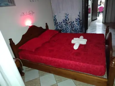 a bed with a red comforter and a cross on it at -= Studio Love =- in Xylophaghou