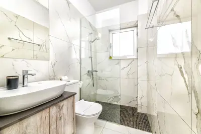 a white bathroom with a sink and a toilet at Olivine Waves in Protaras